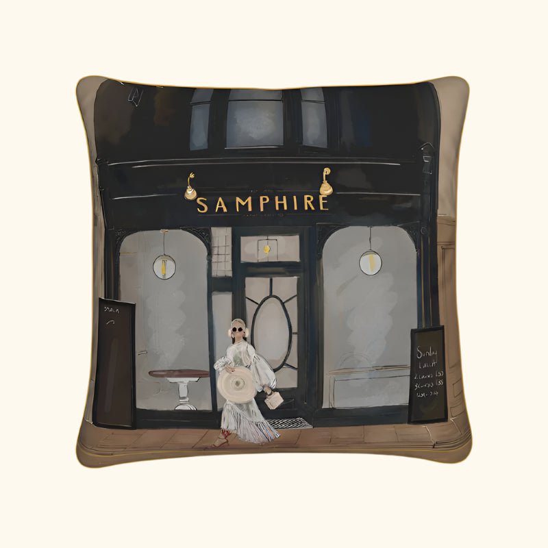 Pillow with a design of a woman walking past a store named 'Samphire' on a white background.