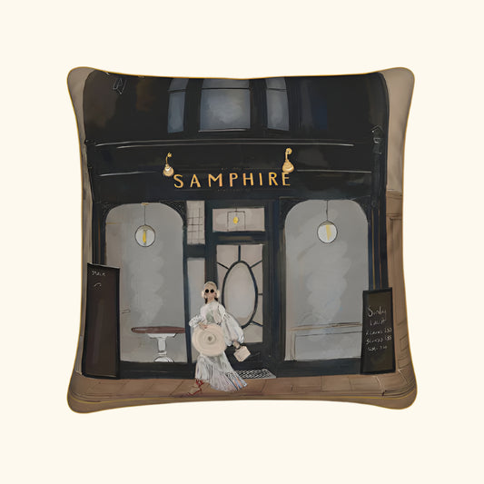 Pillow with a design of a woman walking past a store named 'Samphire' on a white background.